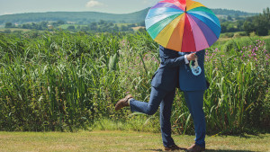Due uomini si abbracciano, nascosti da un ombrello arcobaleno