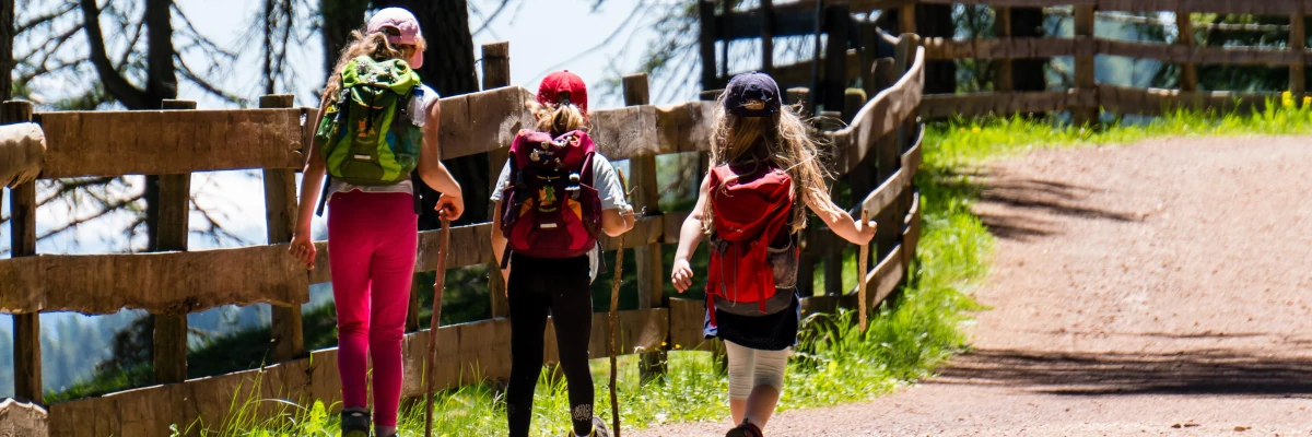 Donna con due ragazzi che fanno escursionismo in montagna. Il tempo per riappropriarsi del proprio respiro e del proprio ritmo fa bene al fisico e alla mente