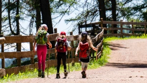 Donna con due ragazzi che fanno escursionismo in montagna. Il tempo per riappropriarsi del proprio respiro e del proprio ritmo fa bene al fisico e alla mente