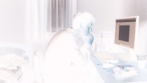 Un ragazzo isolato nella sua camera davanti al computer. L'immagine ha i colori invertiti. L'isolamento sociale volontario si sta diffondendo anche in Italia