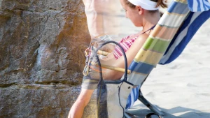 Persona in spiaggia con immagine sovrapposta di arrampicata. Vacanza tra bisogno di riposo e ricerca di esperienze.